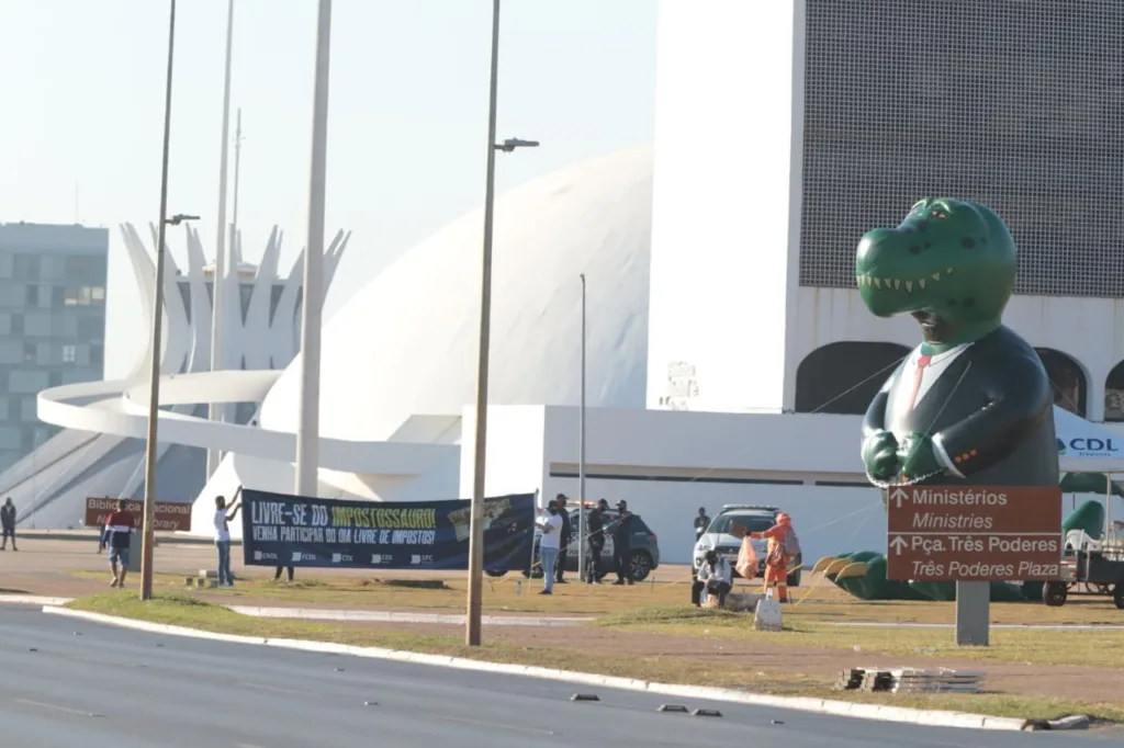 Em ato, federações de lojistas reivindicam uma reforma tributária que simplifique os impostos. Manifestantes adotaram o mascote do "Impostossauro" em ato nesta quinta-feira (27), em frente à Esplanada dos Ministérios - Foto: Divulgação CNDL