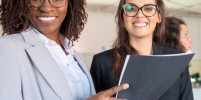 Group of smiling women holding paper documents