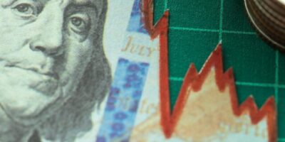 Imagem mostra uma nota de um dólar com gráfico quebrando e moedas ao lado de um tabuleiro verde, demonstrando a crise nos bancos americanos. XPCI11